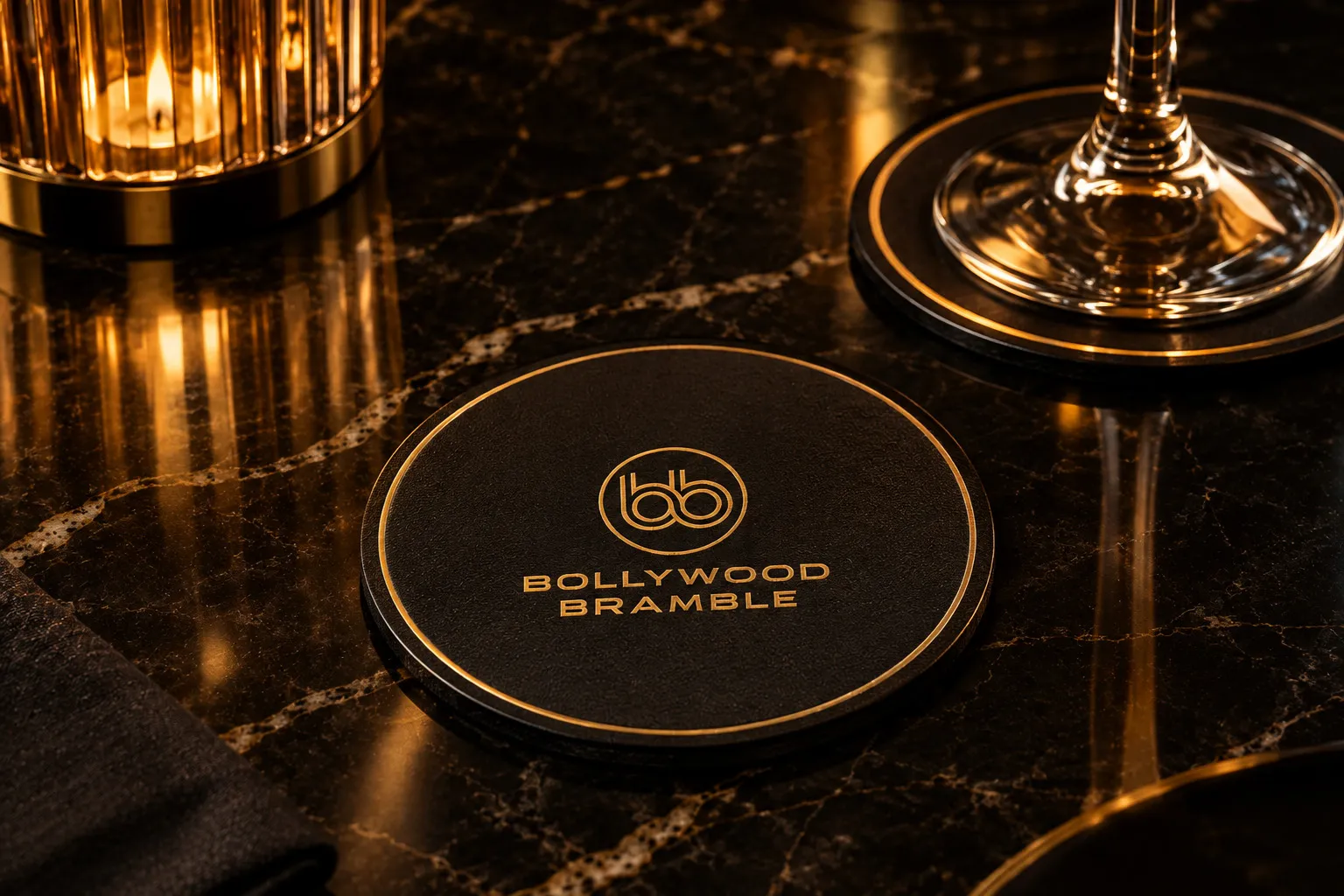 A round black coaster with the logo in gold foil beneath a wine glass.