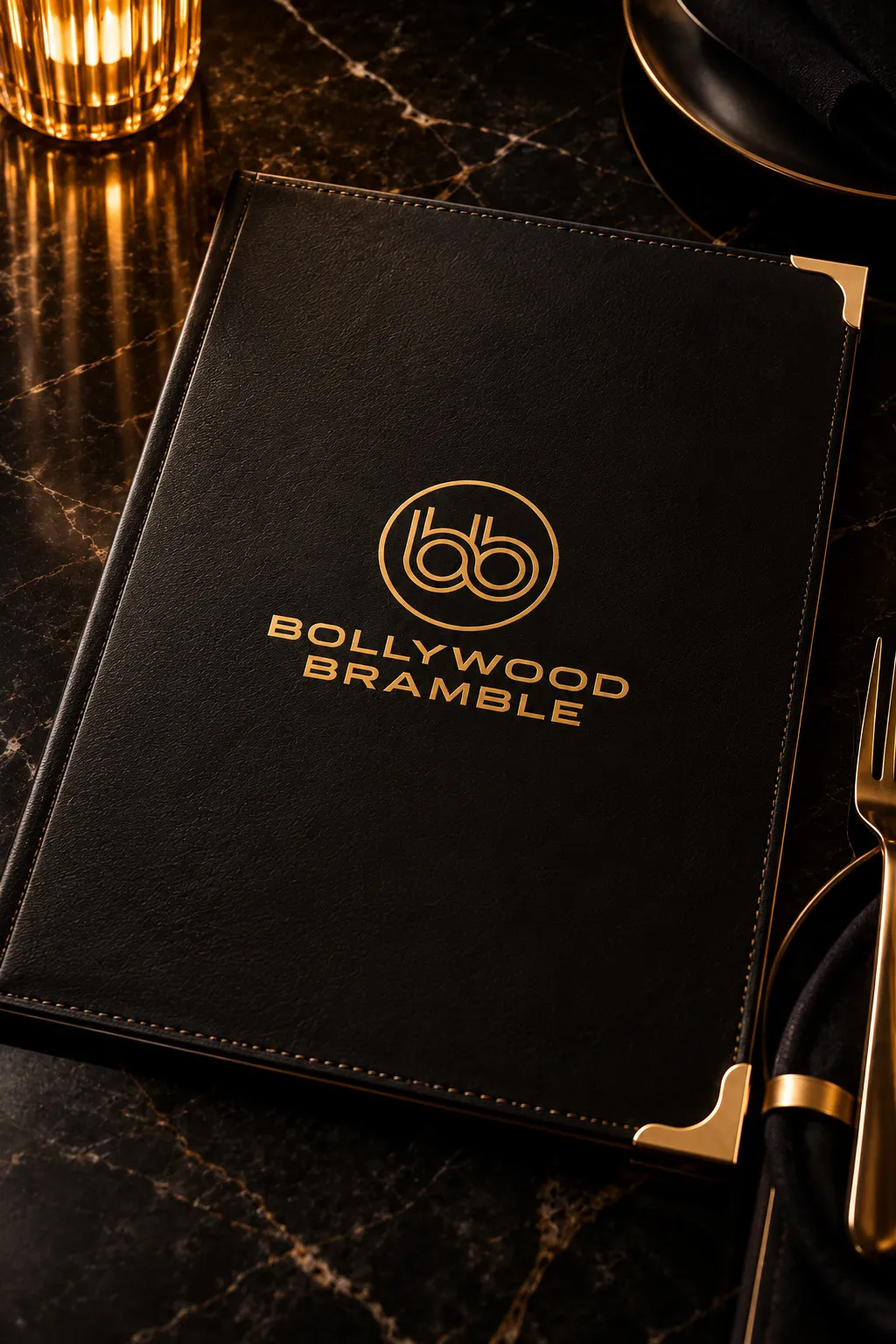A black leather menu folio with gold corners and the Bollywood Bramble logo in gold foil.